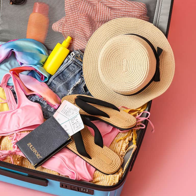 womens items like clothing and hat and passport in a suitcase for travel